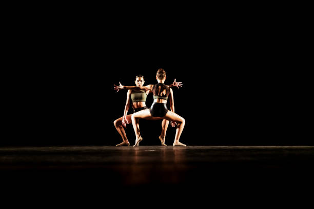 Girl duet performing contemporary dance on dark stage Girl duet performing contemporary dance on dark stage contemporary dance stock pictures, royalty-free photos & images