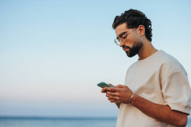 istock Caucasian man on beach with smartphone 1419375891