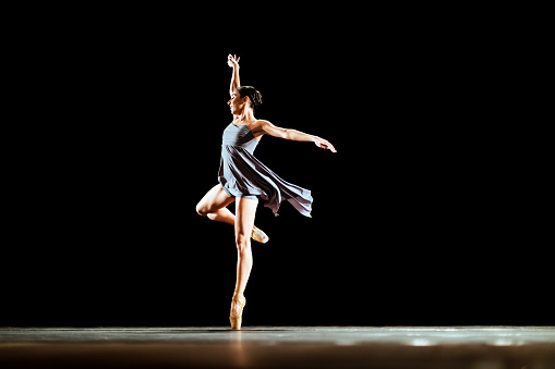 Girl dancing neoclassic ballet on dark stage