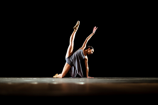 Girl dancing neoclassic ballet on dark stage