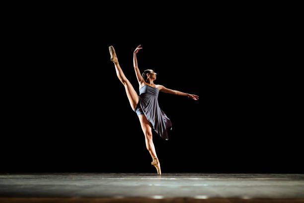 ragazza che balla balletto neoclassico sul palcoscenico scuro - danza classica foto e immagini stock