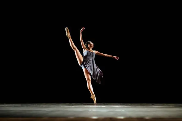 Photo of Girl dancing neoclassic ballet on dark stage