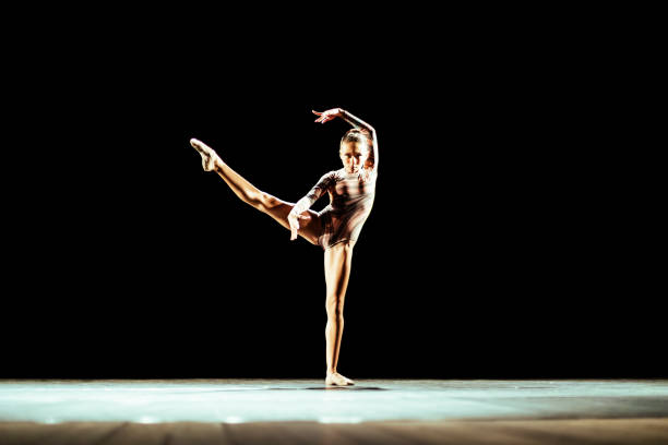 Girl performing contemporary dance on dark stage