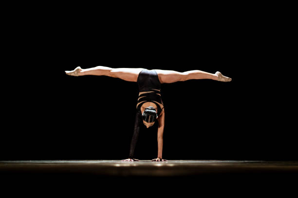 Girl performing contemporary dance on dark stage.