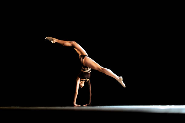Studio shot of young charming girl, rhythmic gymnast training with sports equipment isolated over pink background in neon light filter. Dance, music, emotions, challenges, motivation and ad