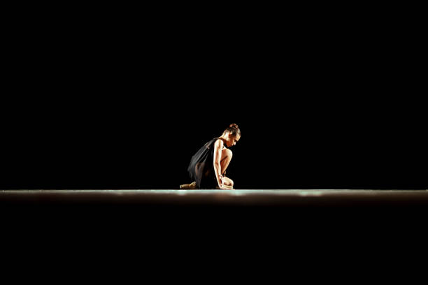 Girl dancing neoclassic ballet on dark stage.