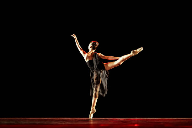 Girl dancing neoclassic ballet on dark stage.
