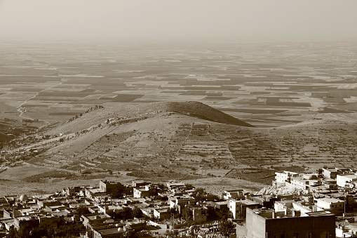 Photo with sepia effect of panoramic view of the Mesopotamian plain and the city of Mardin in the foreground in light haze