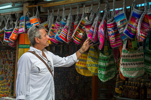 Mature man walking through the city of Santo Domingo, Dominican Republic, while looking at souvenirs.