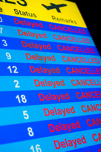 A close-up of a Departure Board monitor with all flights marked as “Delayed and Cancelled”.