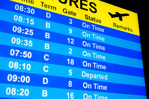 Looking up at a close-up of a Departure Board monitor at all flights “On-Time” or “Departed”.