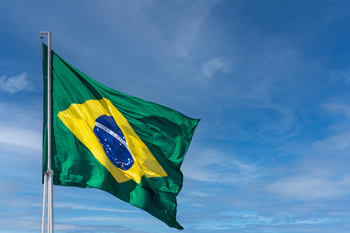 Brazilian flag fluttering in the wind with skies with few clouds. Translation: order and progress in portuguese