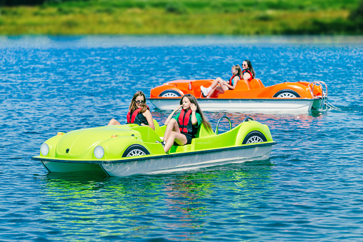 Two pedal boats on a mountain lake with teenagers