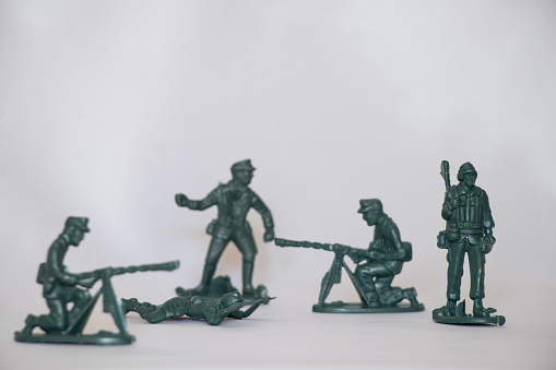 Toy soldier with a radio and a group of fighting soldiers.  The soldiers are in various fighting postures and holding various weapons while ready to engage in battle.