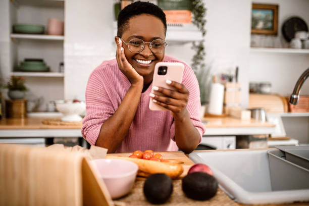 istock Young millennial woman using phone in kitchen while preparing lunch 1419405737