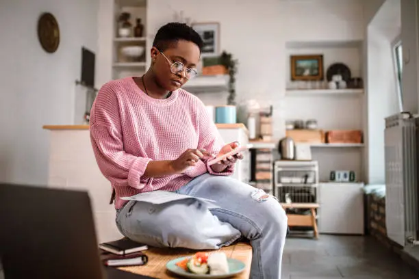 Photo of Young woman doing home finances at home in the morning