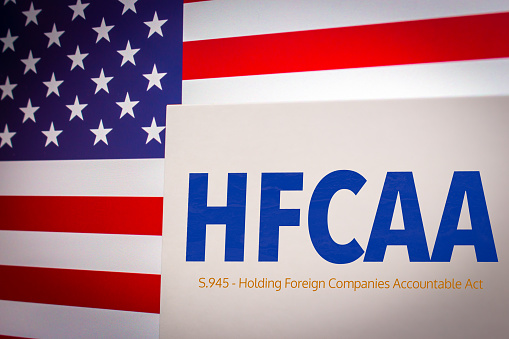 Conceptual keyword HFCAA (Holding Foreign Companies Accountable Act) on card on an US flag background. Chinese businesses in USA concept