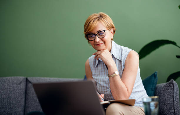 istock Senior Woman Sitting on the Sofa Using the Laptop Computer 1419407797