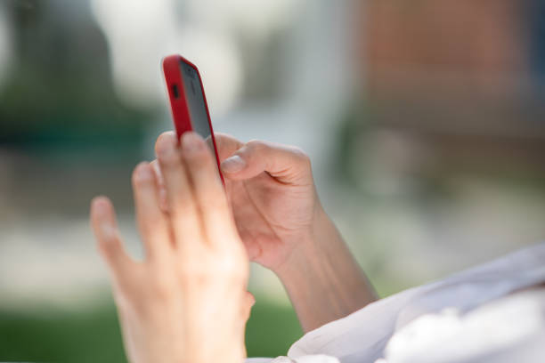 Woman with red hat using mobile phone on sunbed