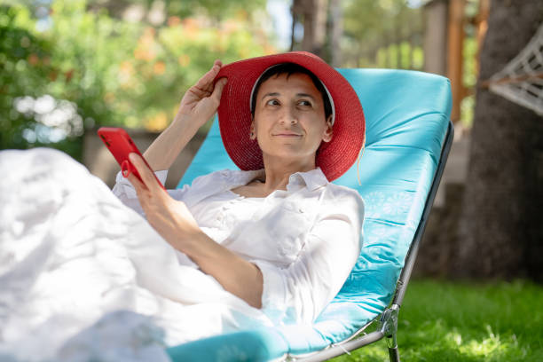 istock Woman sitting on sunbed using mobile phone 1419414539