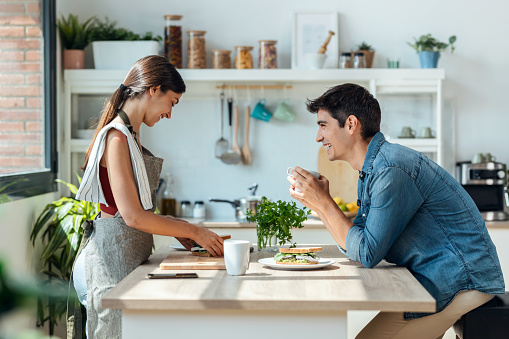 Shot of happy young couple enjoying breakfast while talking in the kitchen at home.