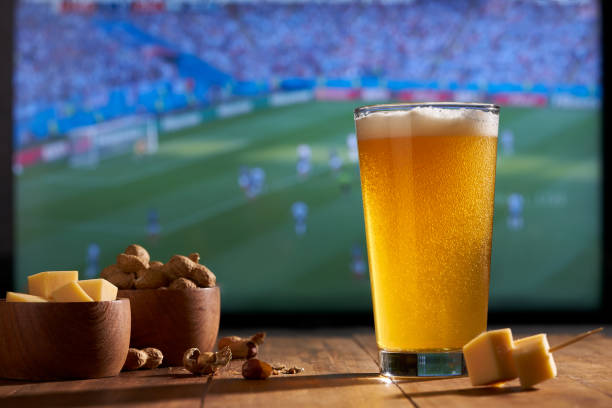 viendo la copa mundial de fútbol en un televisor grande con un vaso de cerveza, cacahuetes y queso - beer nuts fotos fotografías e imágenes de stock