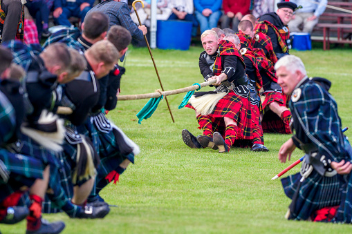 Strathdon, Scotland, UK - August 27, 2022: A tug of war contest at the Lonach Gathering and Games in Scotland.  At the Lonach Gathering, there is traditionally a Tug of War competition between members of the pipe bands, with those participating wearing traditional clothing.  The Gathering, held annually, began with the Lonach Highland & Friendly Society in 1823 and is a popular day out for tourists and local people.