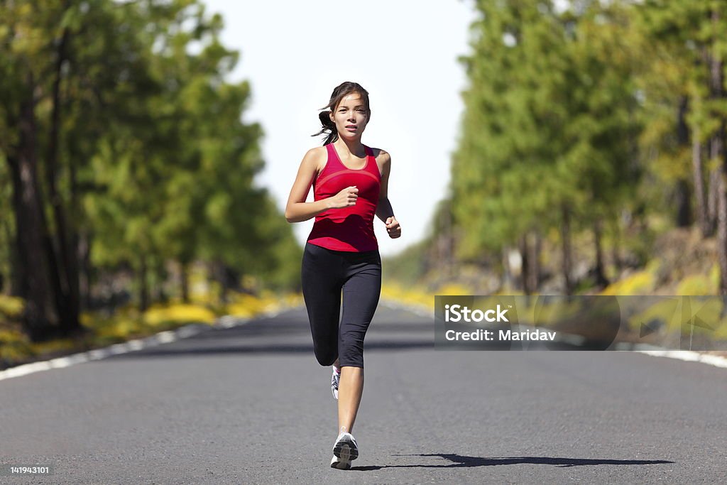 Sport fitness running woman Sport fitness running xwoman jogging during outdoor workout. Beautiful young female athlete runner training for marathon on forest road in spring or summer. Mixed race Caucasian / Chinese Asian xwoman fitness model. Running Stock Photo