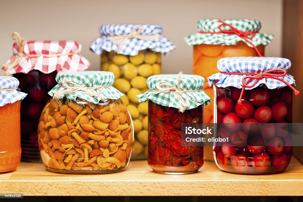 Several jars of preserved fruits and vegetables Preserved fruits and vegetables on the wooden shelf. Apricot Stock Photo