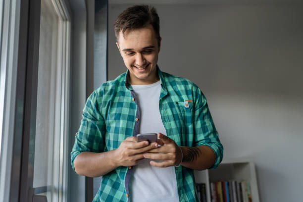 istock One man standing at home using mobile phone to send messages or call 1419443078
