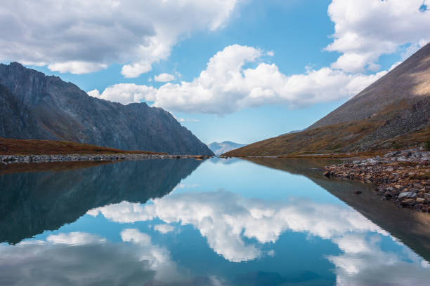istock Tranquil autumn landscape with clouds reflection on smooth mirror surface of mountain lake in high hanging valley. Meditative view from calm alpine lake to mountain vastness. Glacial lake clear water. 1419444627
