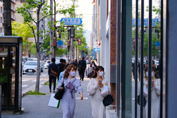 Two fashionable young Japanese women wearing masks while shopping in downtown Kyoto stock photo