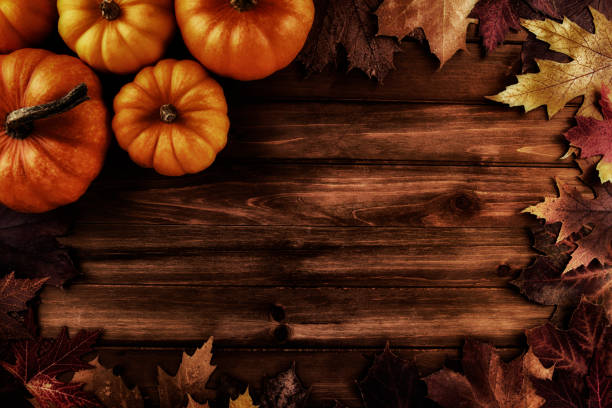 istock Pumpkins with fall leaves over wooden background. 1419447692