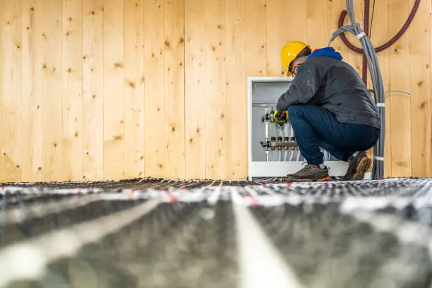 Photo of Plumber mounting underfloor heating manifold