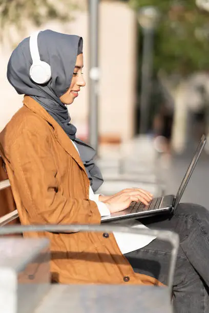 Photo of Muslim woman using a laptop in the steet