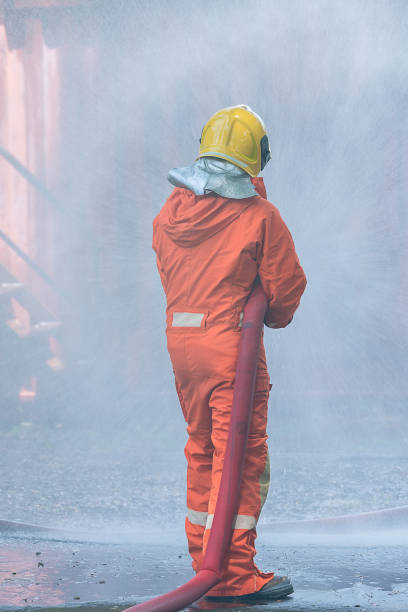 feuerwehrmann sprühen wasser aus dem schlauch für die brandbekämpfung. feuerwehrmann sprüht einen reinen dampf - 18633 stock-fotos und bilder