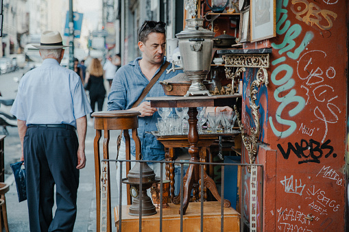 Athens, Greece - July 17, 2022: Tourists and Locals walking on the street in Athens, tourist checking out some antiques in the antique shop.