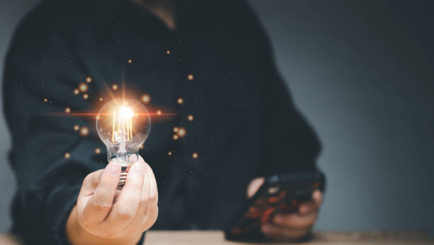 istock Idea innovation and inspiration concept. Hand of man holding illuminated light bulb, concept creativity with bulbs that shine glitter. Inspiration of ideas for sustainable business development. 1419459057