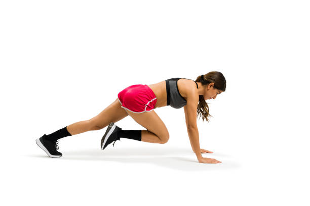 Active young woman exercising with cross training and doing mountain climbers stock photo