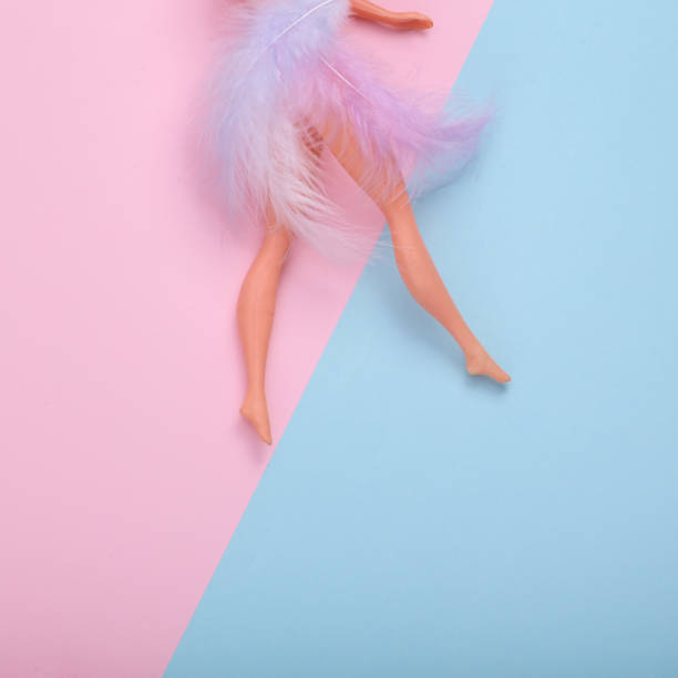 istock Doll feet with feathers on pink blue background. Cretive easter layout. Minimal still life. Flat lay. Top view 1419472627