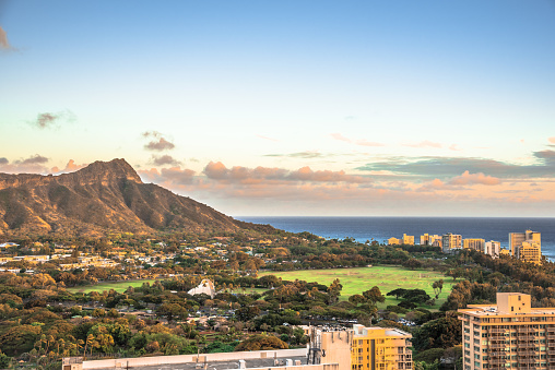 The sun starts to rise over the sand and shore of Waikiki Beach with Diamond Head in the background, Hawaii.