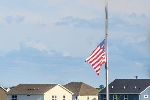 American Flag Flying Half Staff in front of residential buildings.