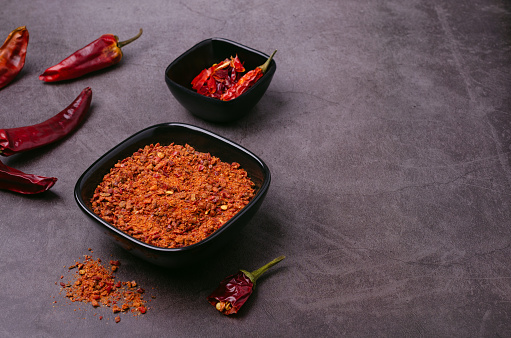 Selection of Exotic Spices with Chili, Star Anise, Cinnamon, Tumeric, Cardamon and rose petals served on wooden spoons on dark surface