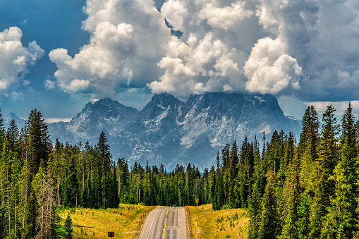A road into Grand Teton National Park, a storm enveloping the peaks of the Teton Mountain Range on a summer afternoon.