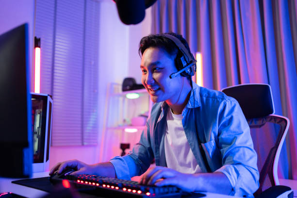 Asian attractive Esport male gamer play online video game on computer. Handsome man gaming player feel happy and excited, enjoy technology broadcast live streaming while plays cyber tournament at home el atractivo jugador masculino asiático de esport juega un videojuego en línea en la computadora. el jugador de juegos de hombre guapo se siente feliz y emocionado, disfruta de la transmisión de tecnología en vivo mientras juega un torneo cibernético