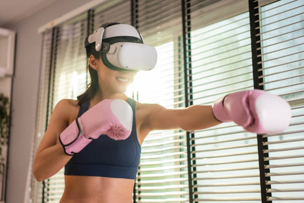 istock Asian sportswoman using innovative technology VR glasses for exercise. Attractive beautiful girl wearing virtual reality headset and holding gaming controller while doing boxing fight workout at home. 1419483119