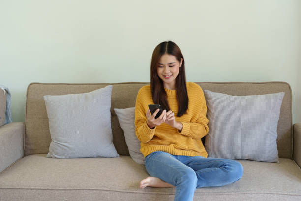 istock woman sitting on sofa at home ready to use mobile phone 1419484991