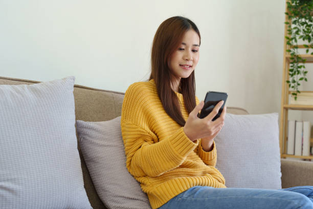 istock woman sitting on sofa at home ready to use mobile phone 1419485027