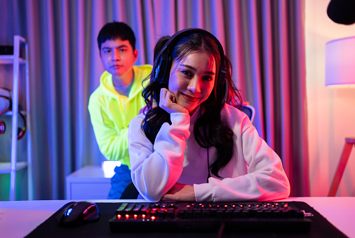 Portrait of Asian Esport man and woman play game on computer together. Attractive young friend gamer player feel happy and enjoy technology broadcast live streaming while play cyber tournament at home