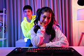 Portrait of Asian Esport man and woman play game on computer together. Attractive young friend gamer player feel happy and enjoy technology broadcast live streaming while play cyber tournament at home